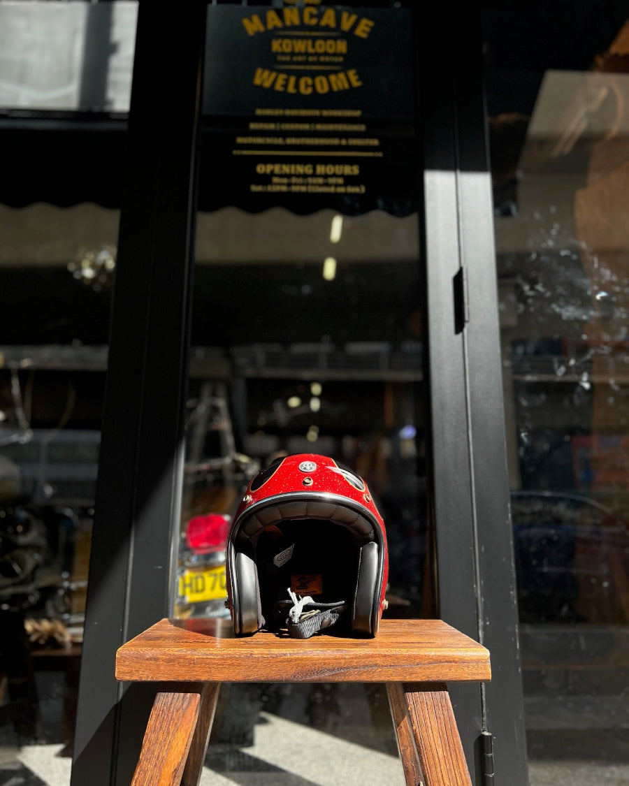 Red motorcycle helmet on a wooden stand with a blurred background of a store entrance.