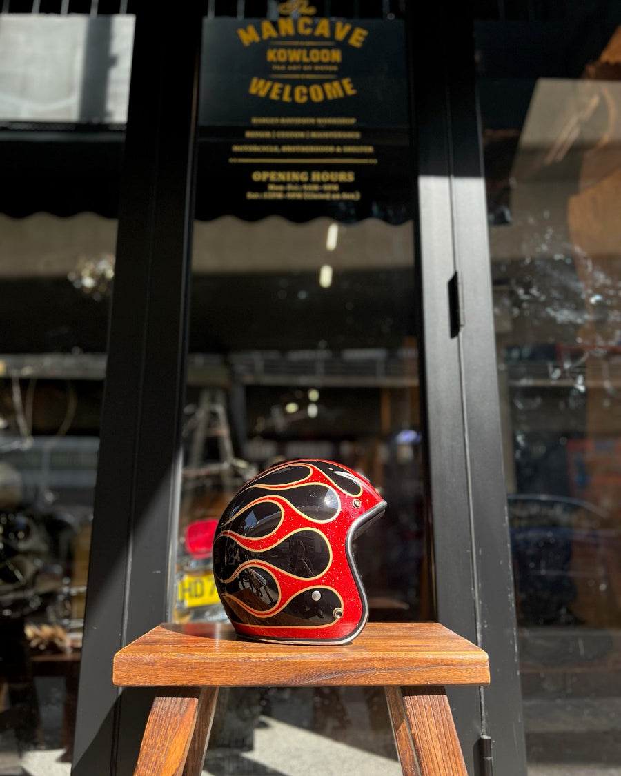 Decorative helmet with flame design on a wooden stool in front of a store entrance.