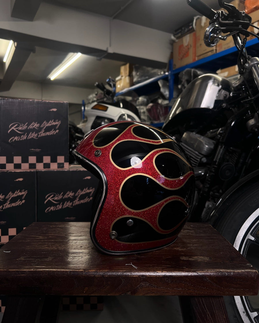Flamed helmet on a wooden surface with a motorcycle in the background