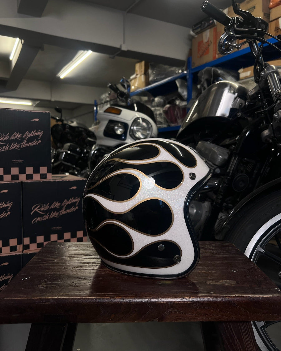 Black and white helmet with flame design on a wooden table in a garage setting