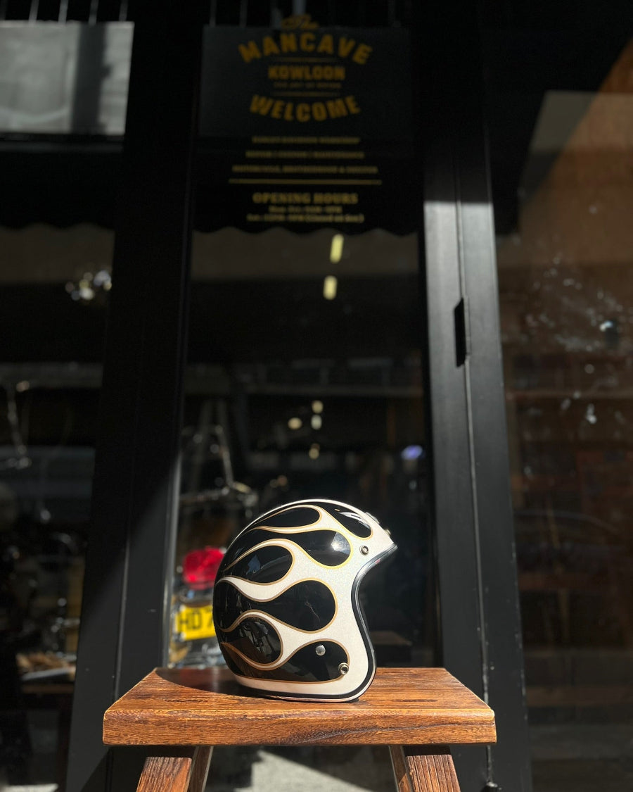 Decorative helmet with flame design on a wooden stand in front of a 'Man Cave' sign.