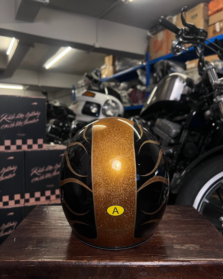 Decorative helmet with gold and black design on a wooden surface in a warehouse setting.