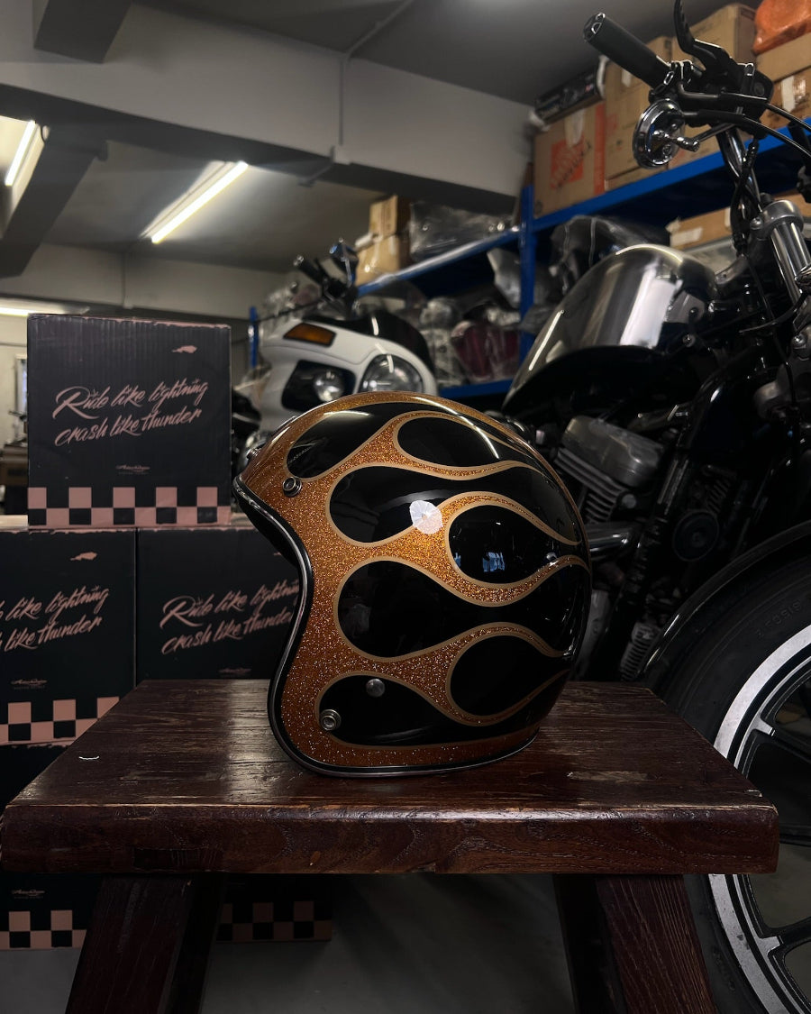 Motorcycle helmet with flame design on a wooden stand in a garage setting
