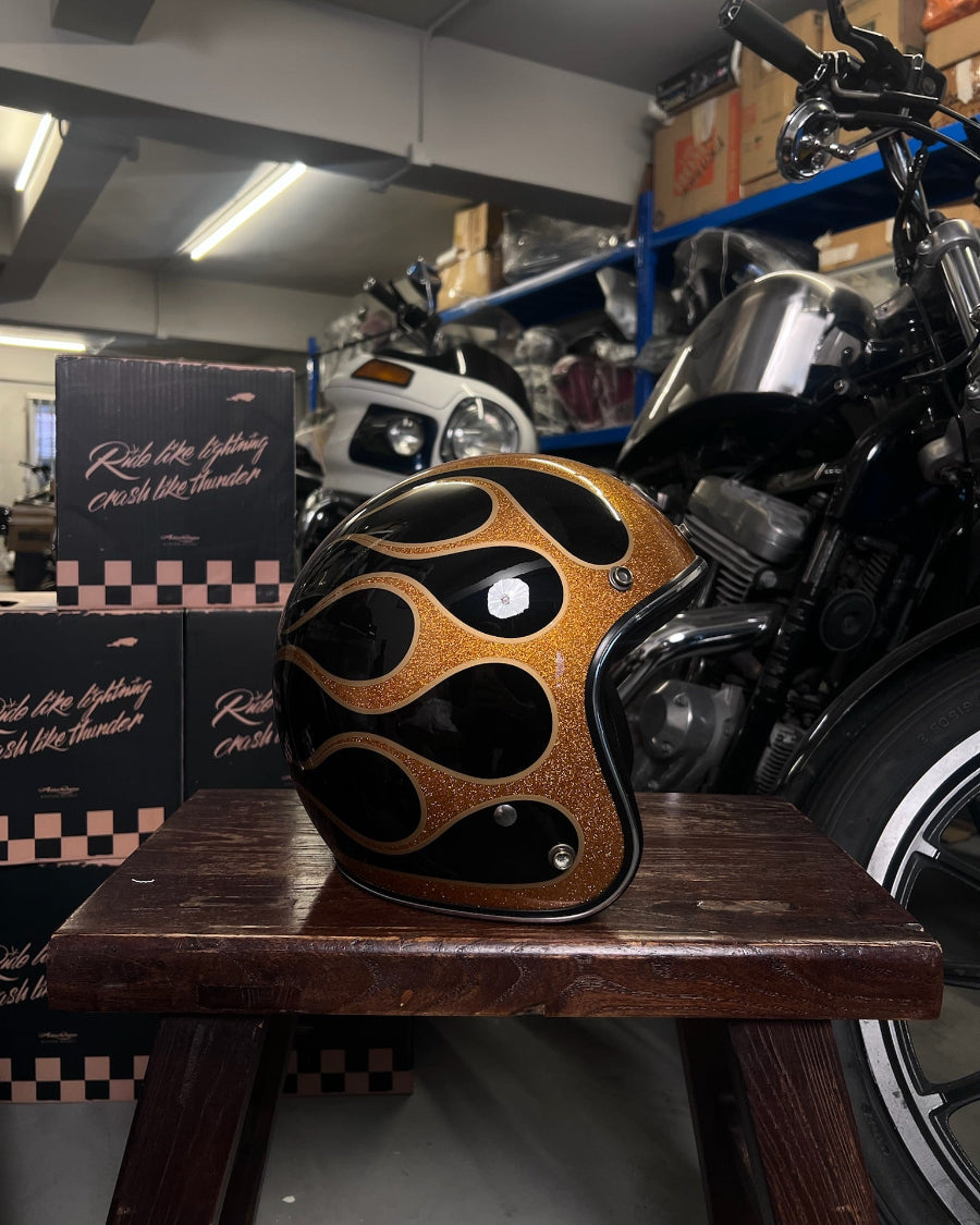 Motorcycle helmet with flame design on a wooden stool in a garage setting