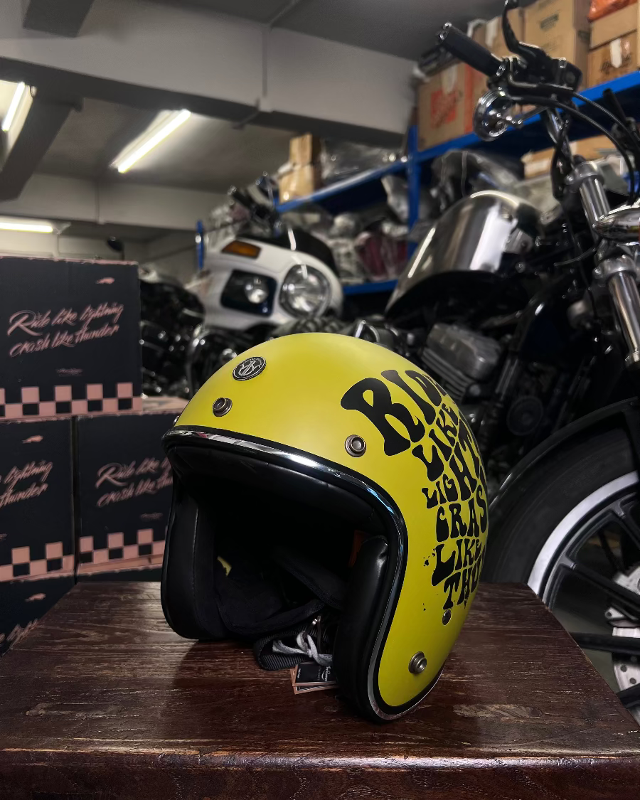 Yellow motorcycle helmet with text on a wooden surface in a garage setting