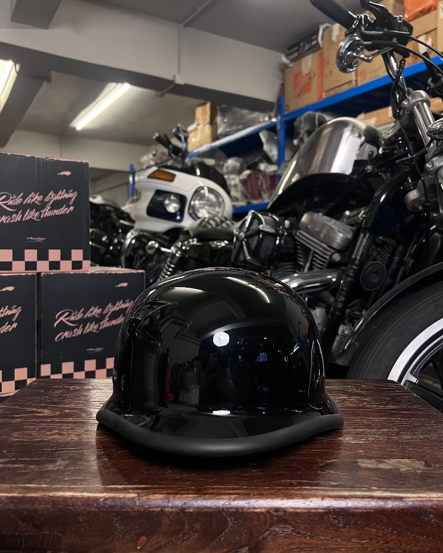 Black helmet on a wooden surface with motorcycles in a garage setting