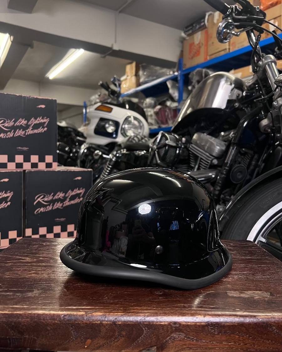 Black helmet on a wooden surface with motorcycles and boxes in the background