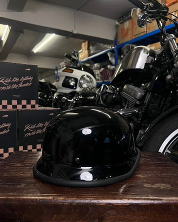 Black motorcycle helmet on a wooden surface with motorcycles in the background