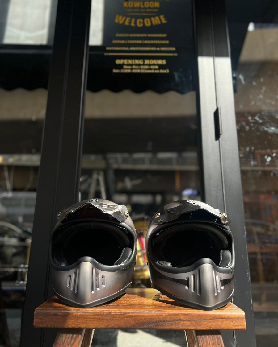 Two black motorcycle helmets on a wooden block with a blurred background