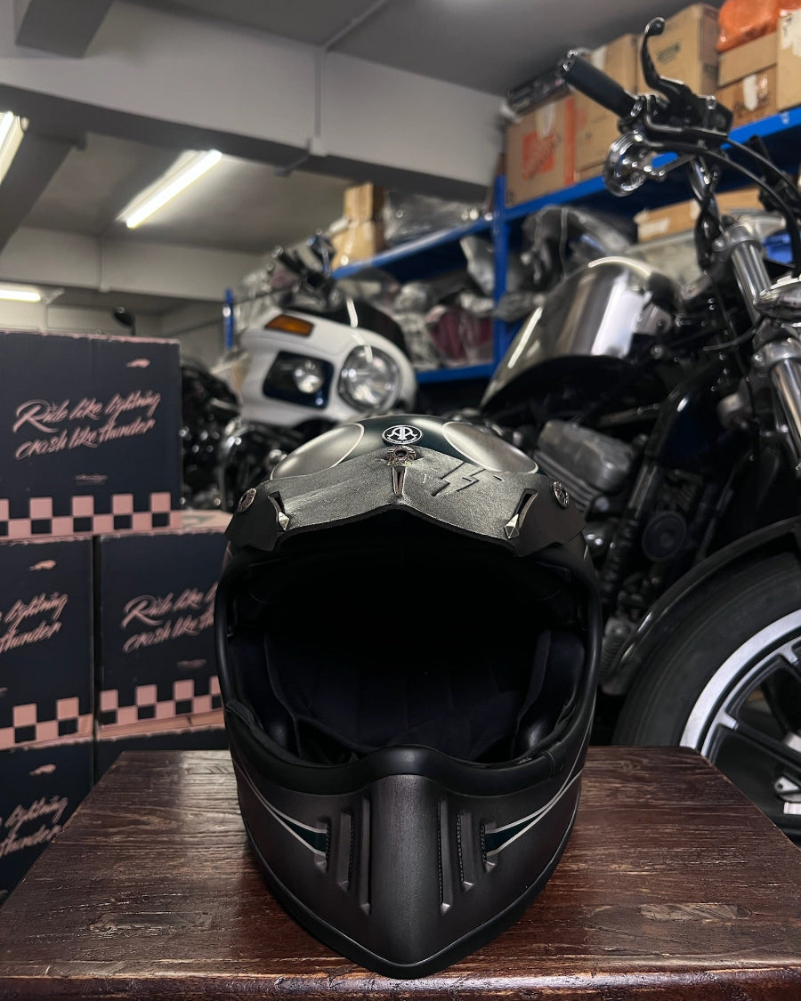 Black motorcycle helmet with visible branding on a wooden surface in a garage setting.