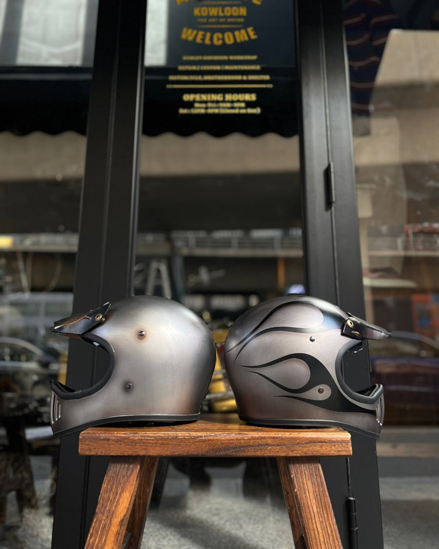 Two motorcycle helmets on a wooden stool with a blurred background