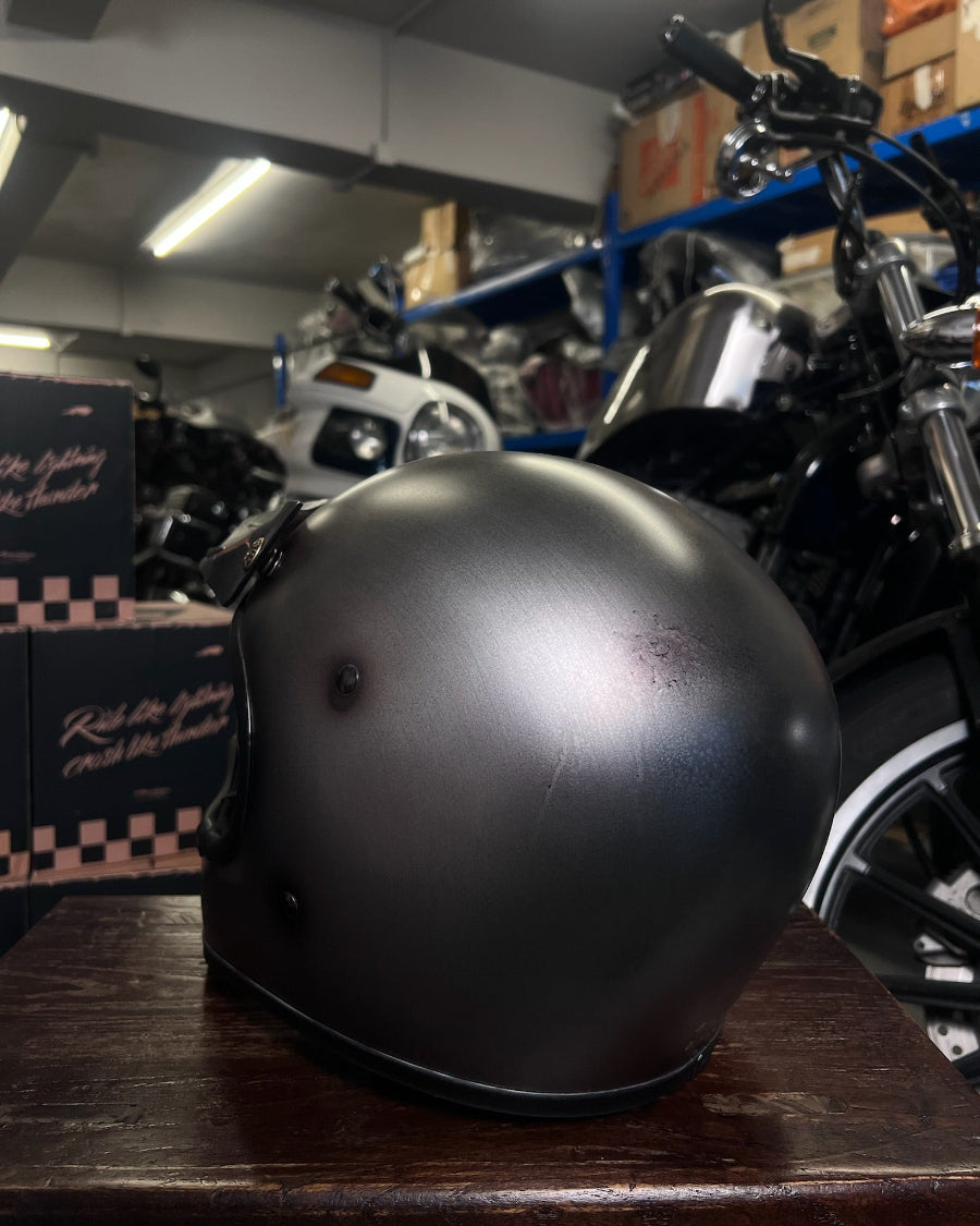 Black helmet on a wooden surface with a motorcycle in the background