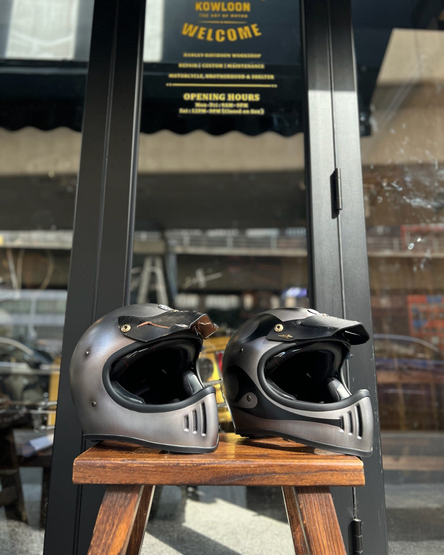 Two motorcycle helmets on a wooden stool with a blurred background
