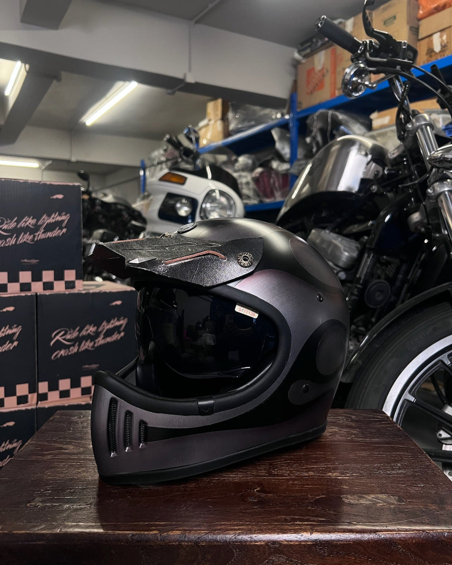 Black helmet on a wooden surface with motorcycles and boxes in the background