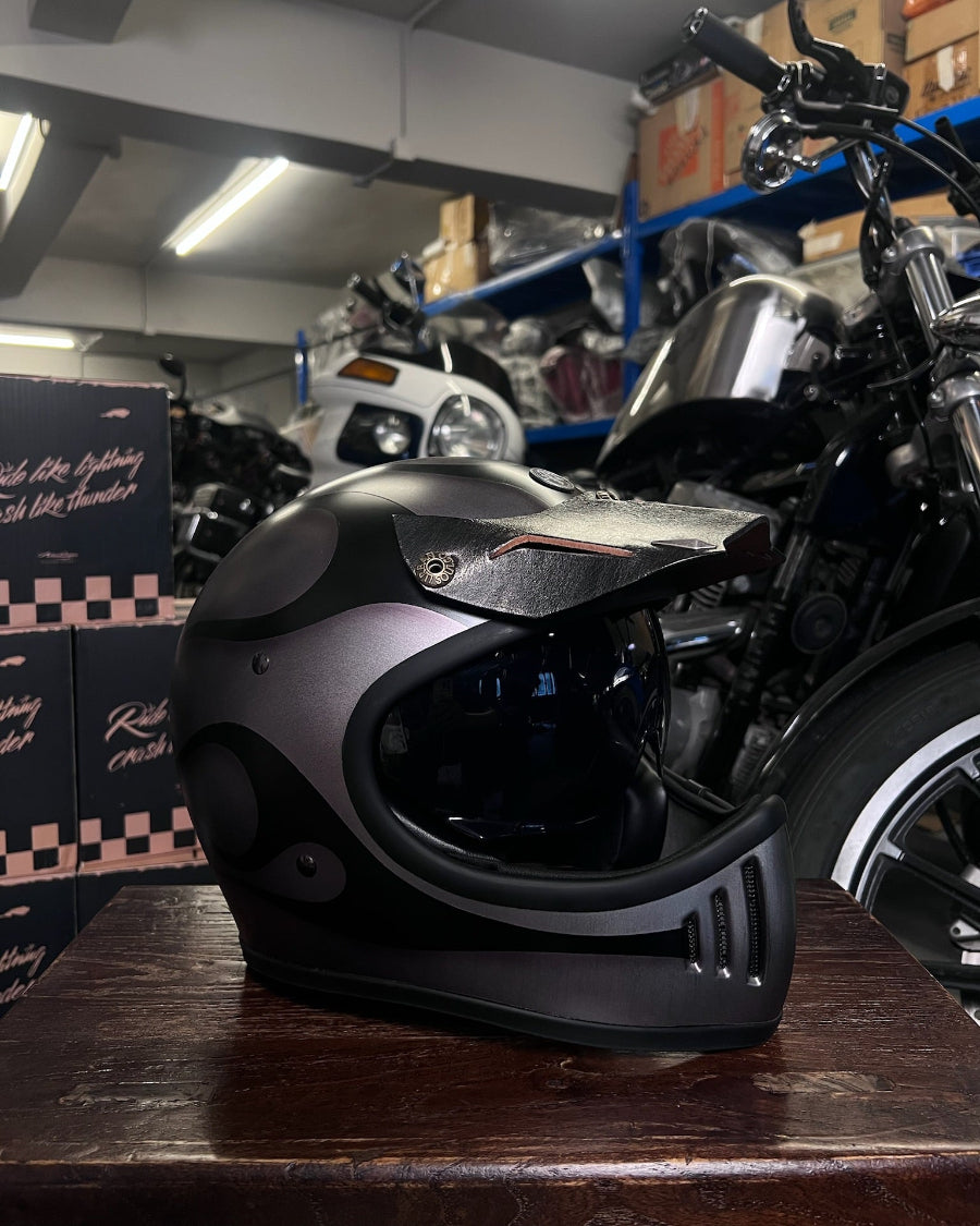 Motorcycle helmet on a wooden surface with a motorcycle in the background