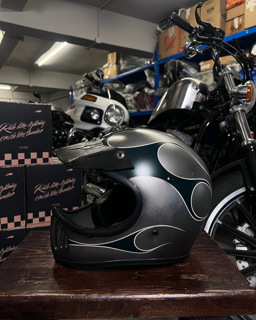 Black and gray motorcycle helmet on a wooden surface with a motorcycle in the background.