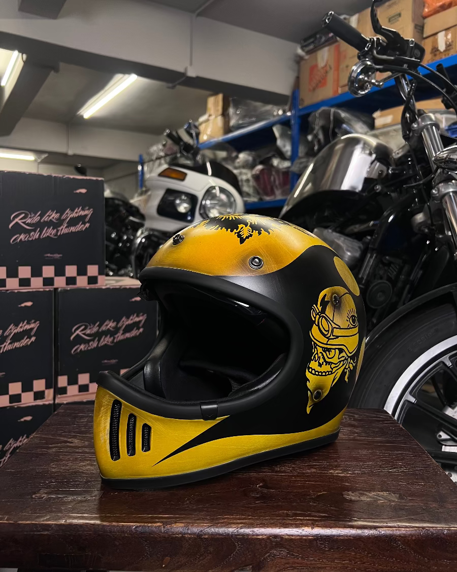 Yellow and black helmet on a wooden surface with a motorcycle in the background