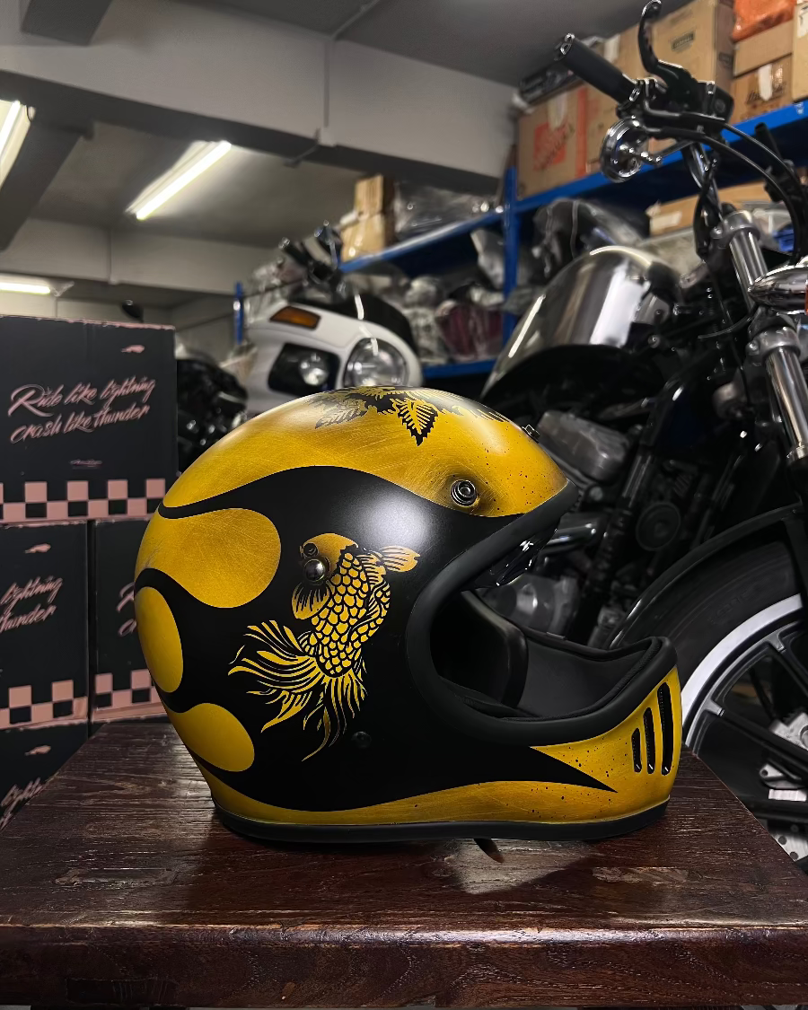 Yellow and black motorcycle helmet with a design on a wooden surface in a warehouse setting.