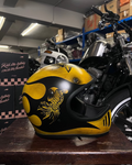 Yellow and black motorcycle helmet with a design on a wooden surface in a warehouse setting.