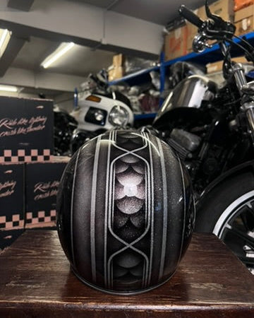 Black and white motorcycle helmet on a wooden surface with motorcycles and boxes in the background