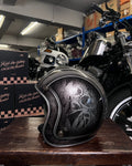 Black motorcycle helmet with skull design on a wooden surface in a garage setting