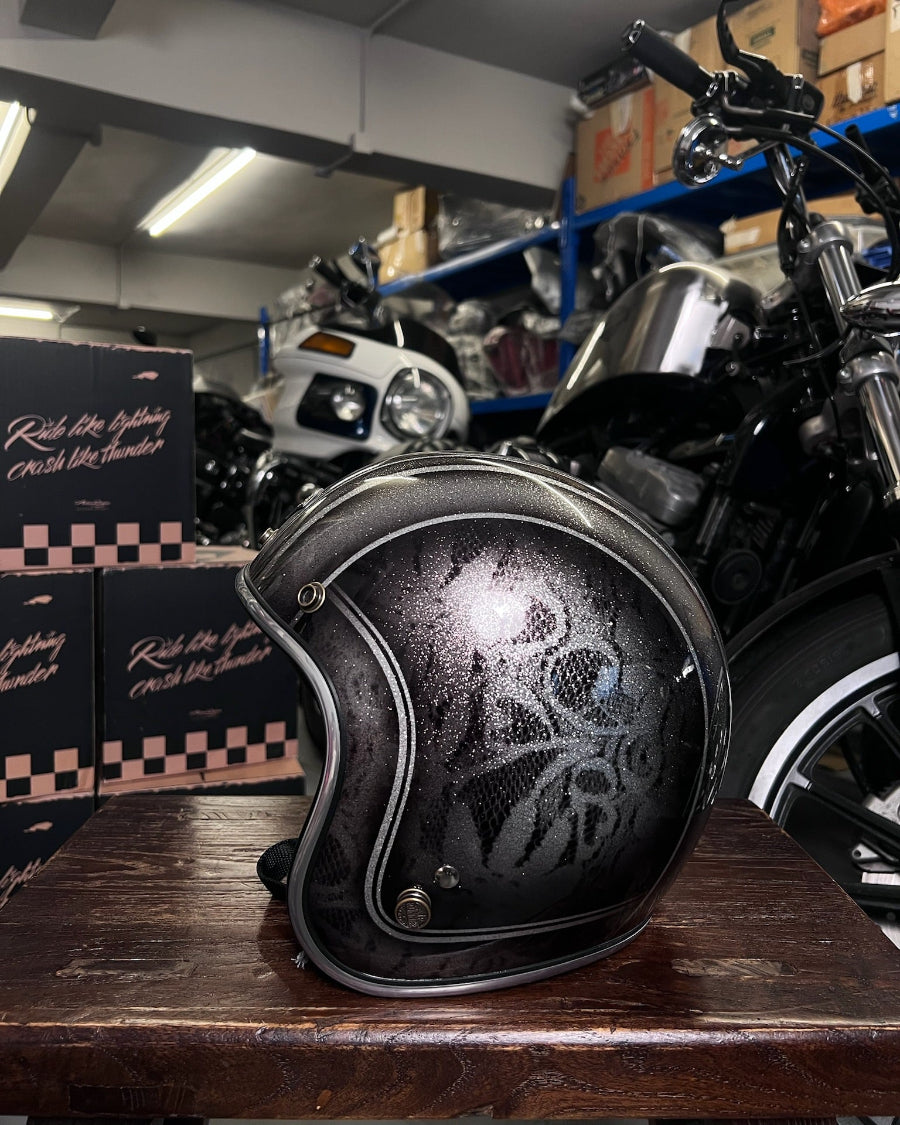 Black motorcycle helmet with skull design on a wooden surface in a garage setting