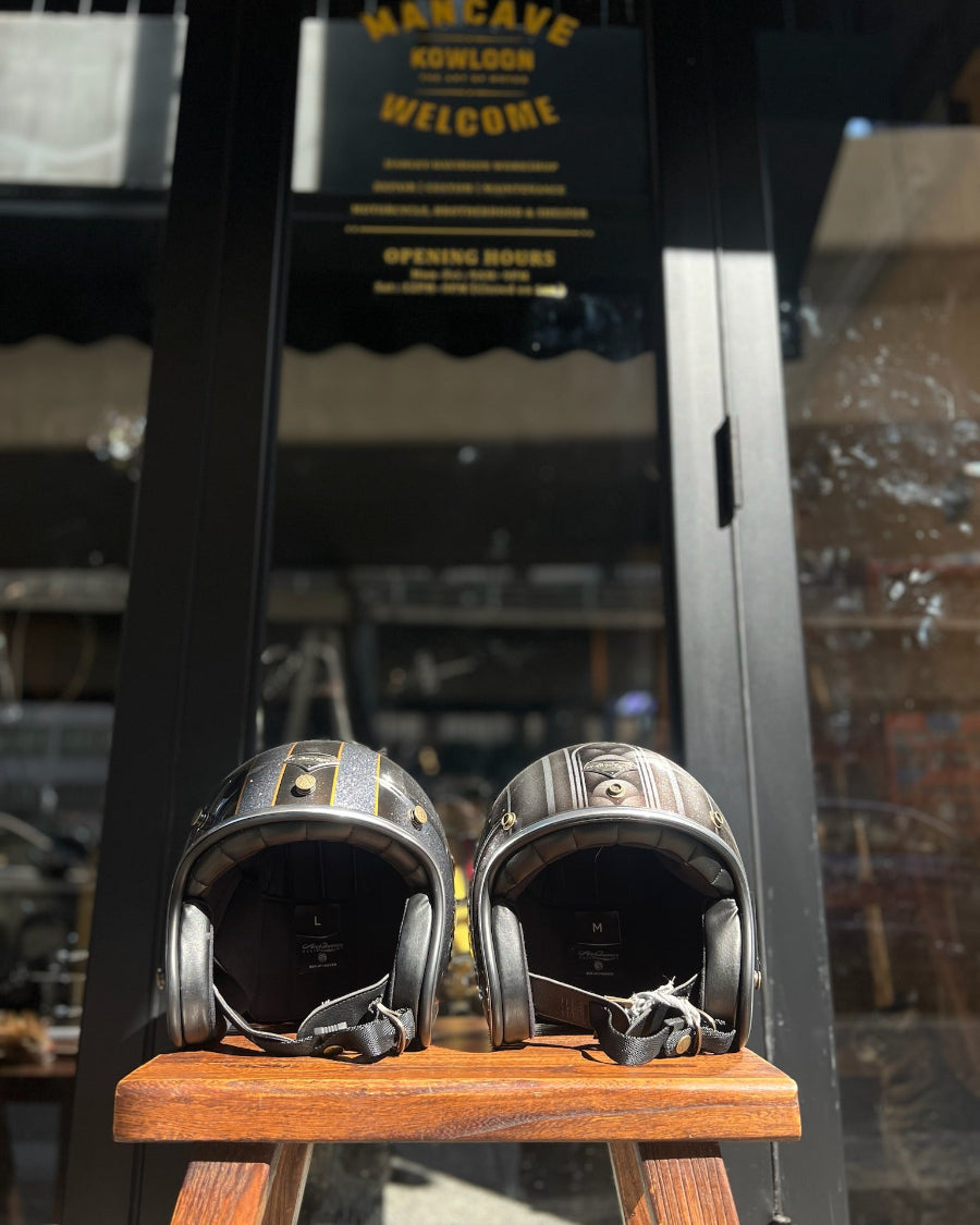 Two motorcycle helmets on a wooden stand with a blurred background