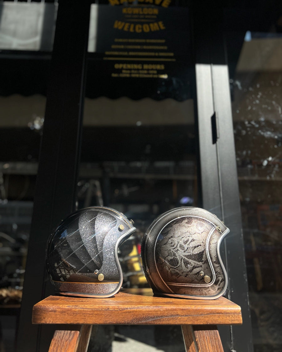 Two decorative helmets on a wooden stand with a blurred background