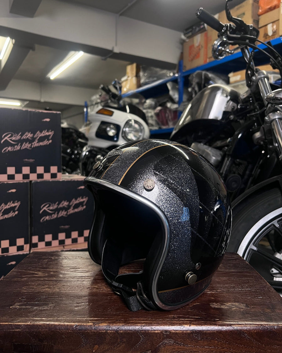Black motorcycle helmet on a wooden surface with a motorcycle and boxes in the background