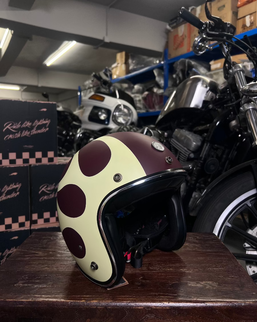 Polka dot helmet on a wooden surface with a motorcycle in the background