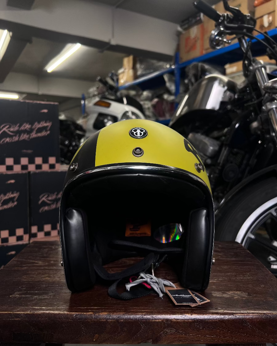 Yellow and black helmet on a wooden surface with motorcycles in the background