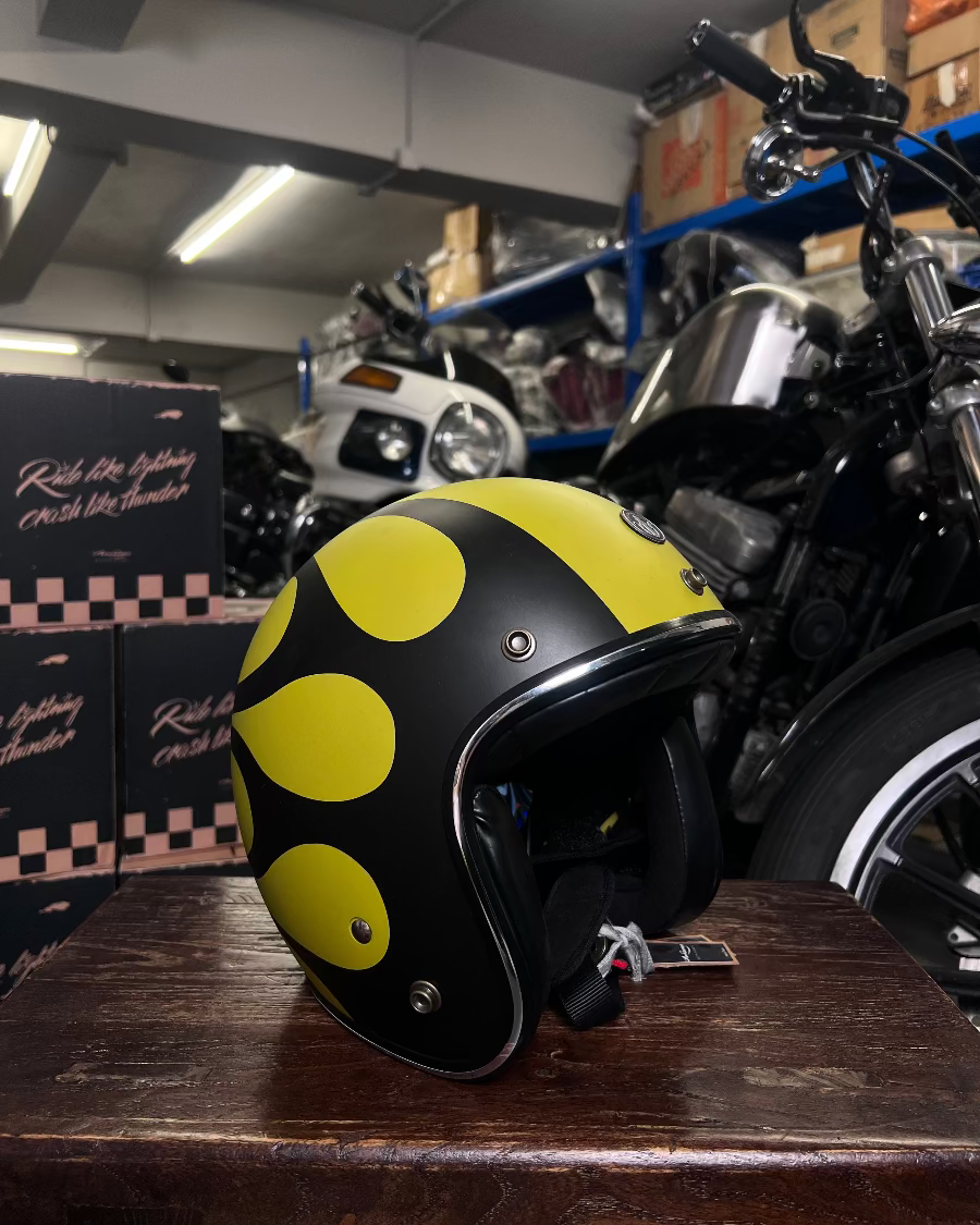 Black and yellow helmet on a wooden surface with motorcycles in a garage setting