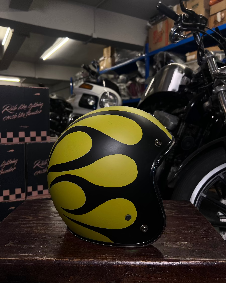 Yellow and black helmet on a wooden surface with a motorcycle in the background