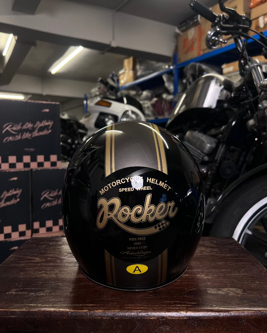 Black motorcycle helmet with gold text on a wooden surface in a garage setting