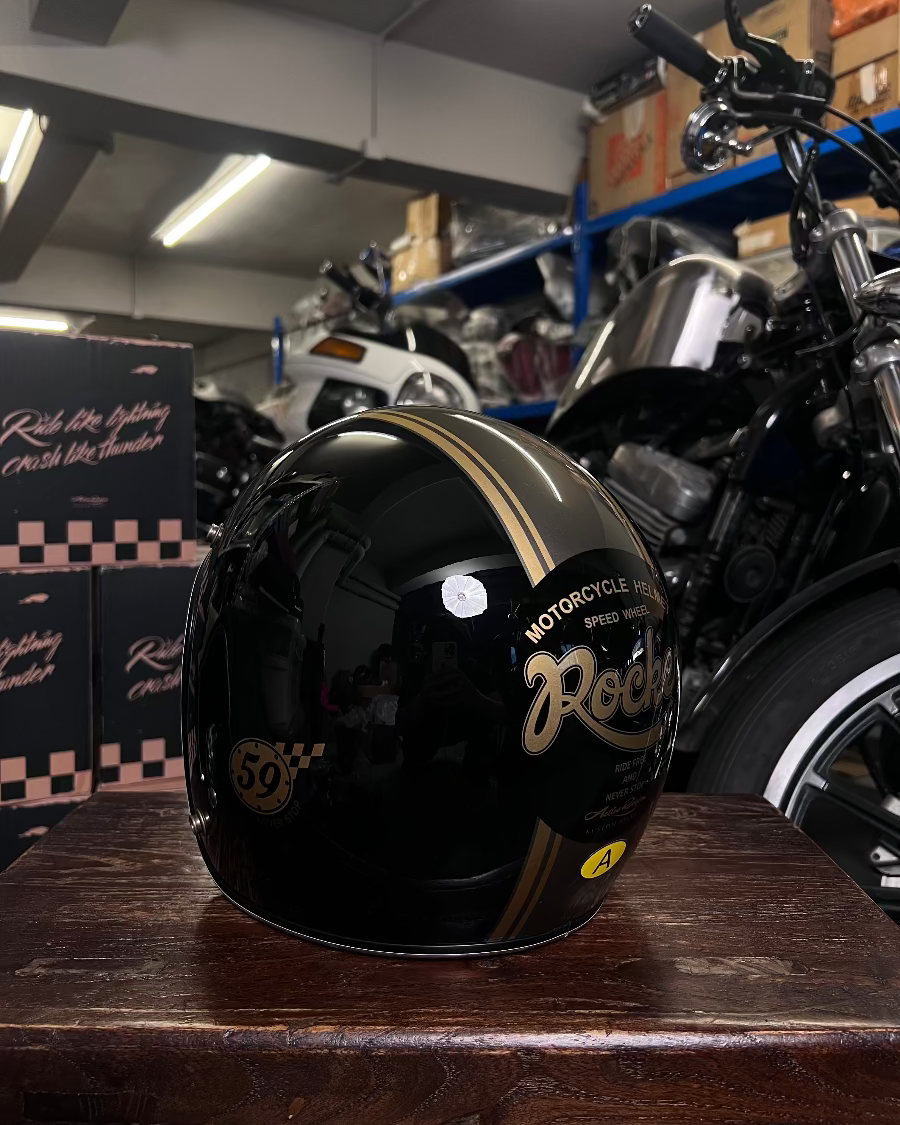 Black motorcycle helmet with gold text on a wooden surface in a garage setting