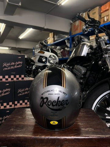 Motorcycle helmet with 'Rocker' branding on a wooden surface in a garage setting.