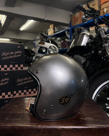 Silver helmet with a logo on a wooden surface in a garage setting