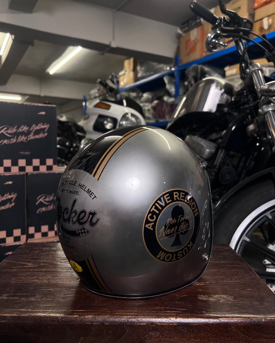 Silver motorcycle helmet with text on a wooden surface in a garage setting