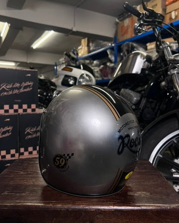 Silver motorcycle helmet with black text on a wooden surface in a garage setting.