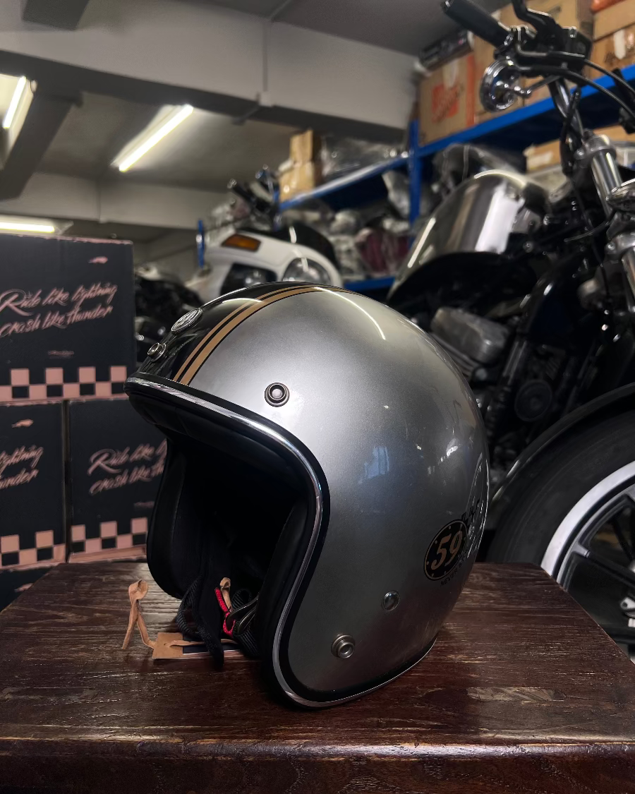 Silver helmet on a wooden surface with a motorcycle in the background