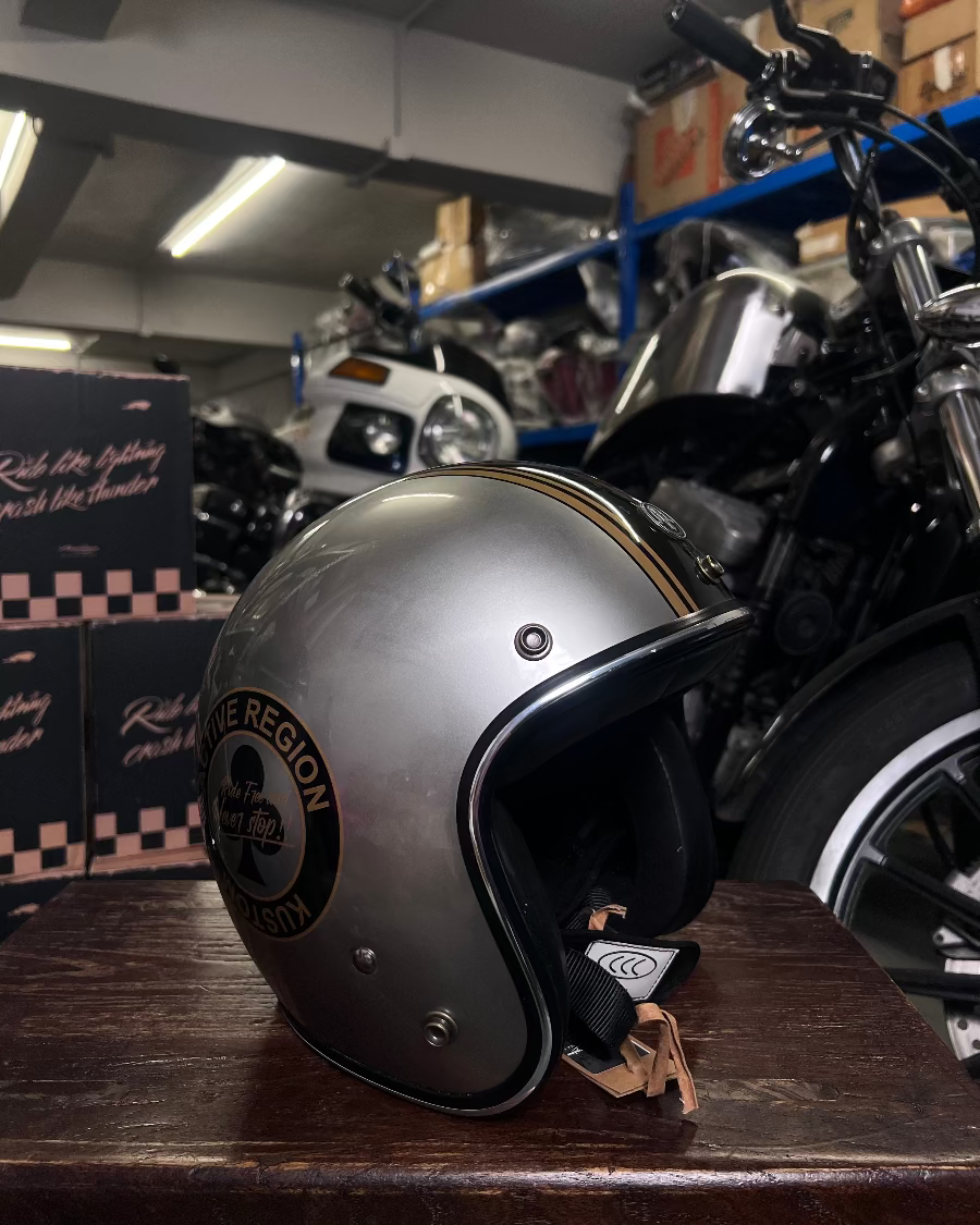 Silver helmet with 'The Region' logo on a wooden surface in a garage setting.