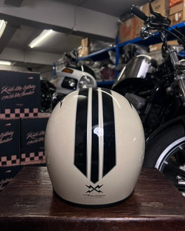 White motorcycle helmet with black stripes on a wooden surface in a garage setting