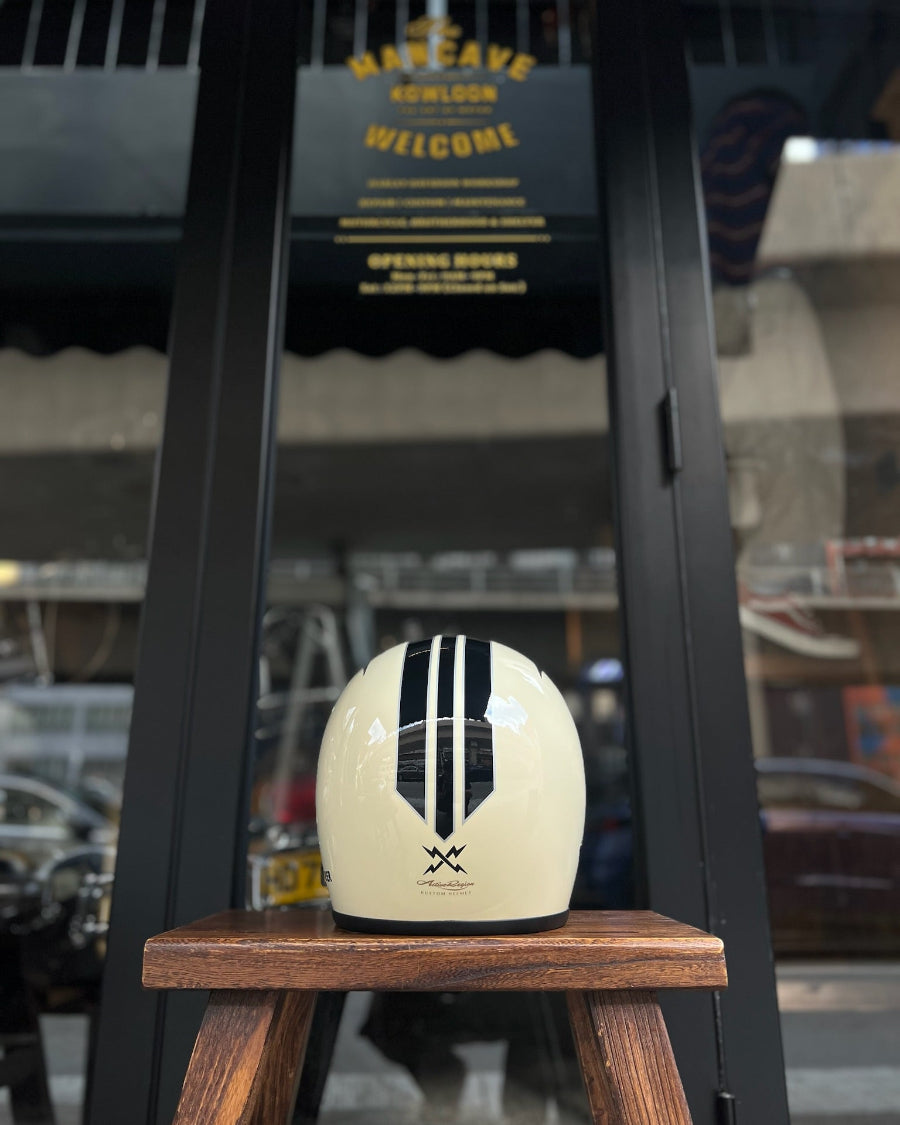 White helmet with black stripes on a wooden stand in front of a store entrance.