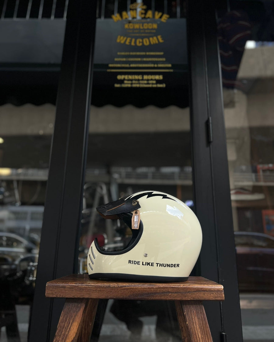 White motorcycle helmet with black accents on a wooden stool in front of a store entrance.