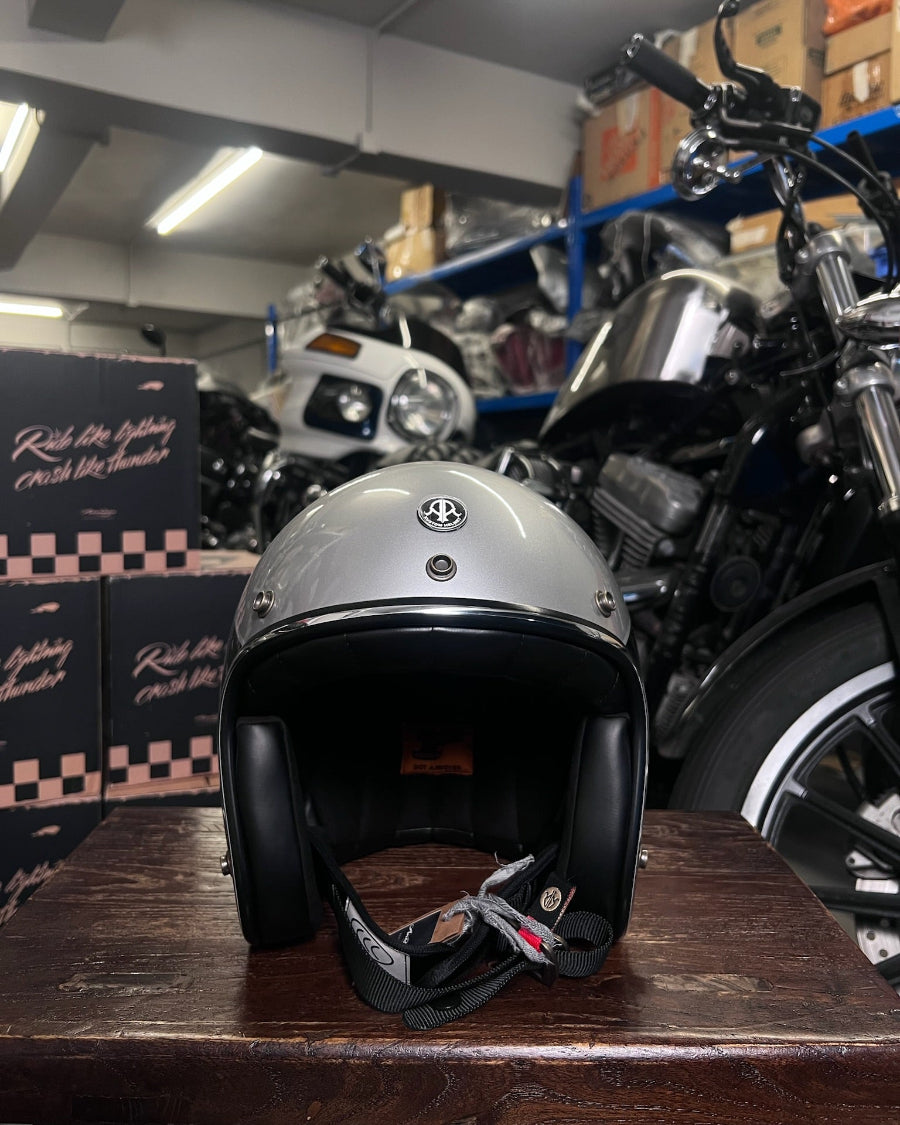 Silver helmet on a wooden surface with motorcycles in the background