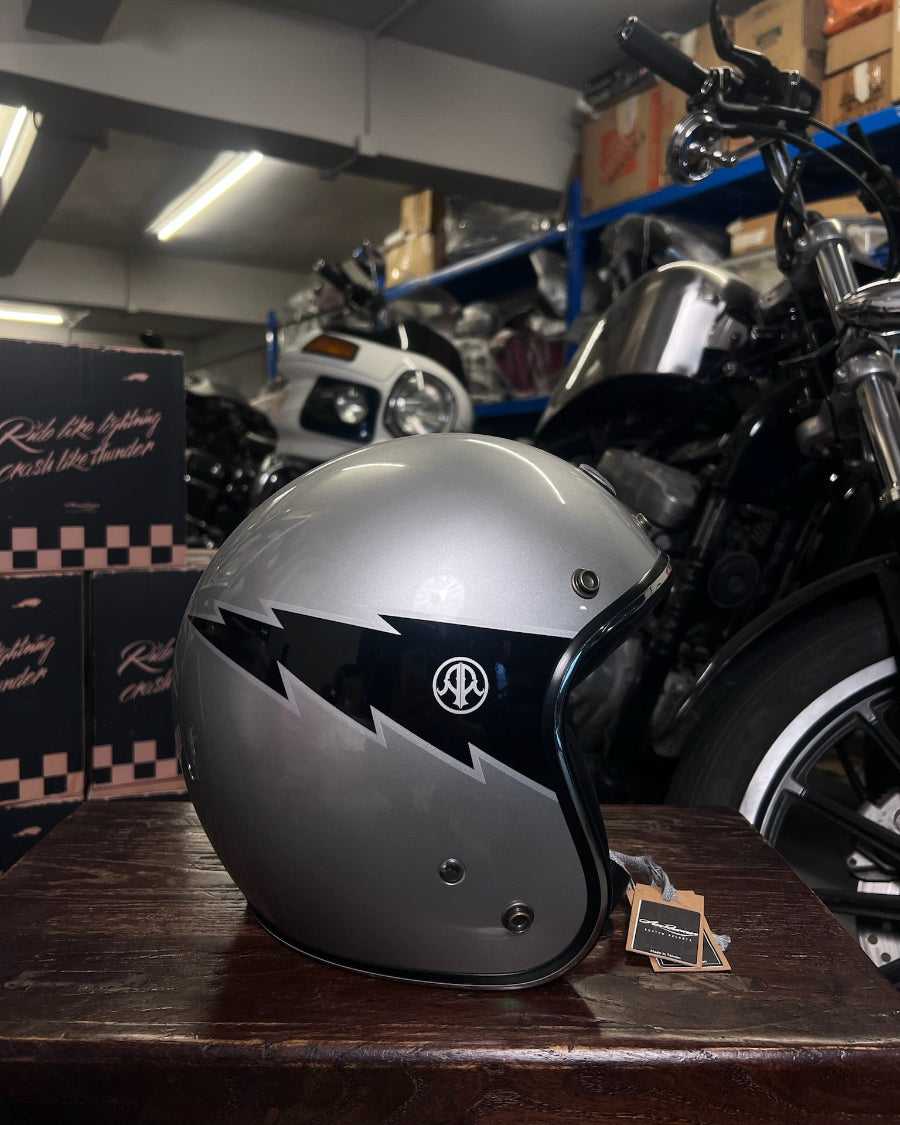 Silver motorcycle helmet with black accents on a wooden surface in a garage setting.