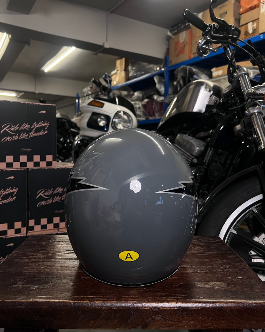 Black motorcycle helmet with a yellow label on a wooden table in a garage setting.