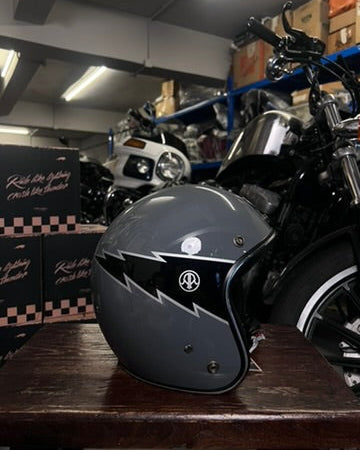 Black motorcycle helmet on a wooden surface with a motorcycle in the background.