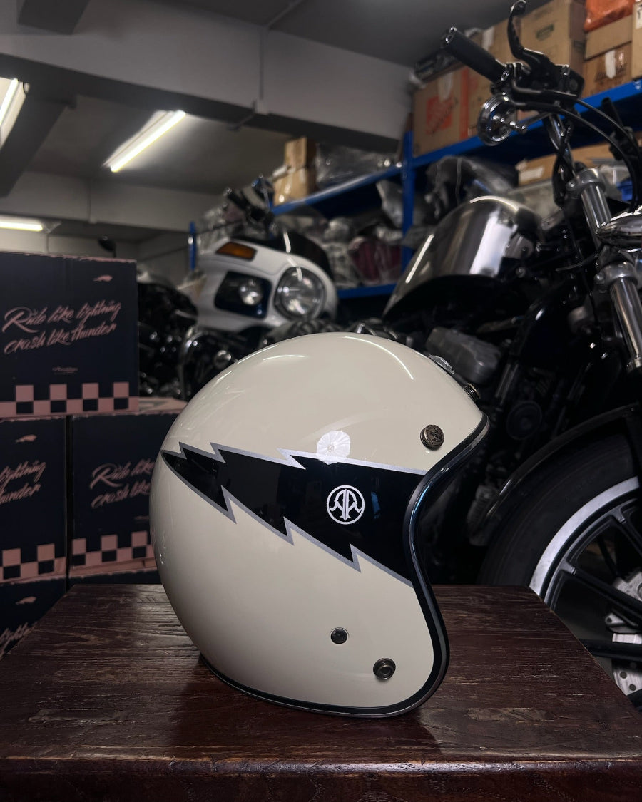 White motorcycle helmet with black designs on a wooden surface in a garage setting.
